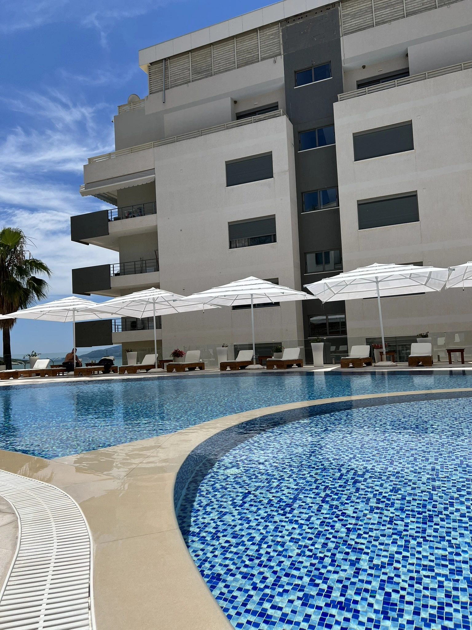 Curved mosaic-tiled outdoor pool with sea view at Harbour Hotel Saranda